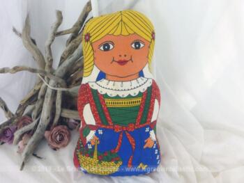 Voici une poupée chiffon coussin représentant une petite fille portant un panier de cerises et un grand noeud bleu dans ses cheveux blonds de 40 x 24 x 12 cm.