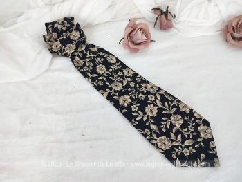 Voici une ancienne cravate vintage marine noire décorée de fleurs beiges et écrues, de la marque "Création Fred Gil -Paris"  et 100% polyester.  Pour hommes ou femmes !