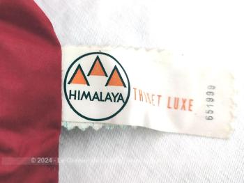 Édredon vintage de 90 x 150 cm habillé d'un tissus en coton rouge portant l'étiquette de la marque "Himalaya Thibet Luxe" et rembourré par du duvet et plumes maintenus par des coutures piqués formant un léger quadrillage.  Top vintage .