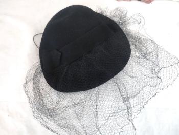 Voici un ancien chapeau en feutre noir forme un peu plate et mis en valeur par un ruban en feutre qui maintient une double voilette. Datant des années 50/60, c'est un beau chapeau de la modiste "Duvelty" à Paris.