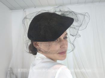 Voici un ancien chapeau en feutre noir forme un peu plate et mis en valeur par un ruban en feutre qui maintient une double voilette. Datant des années 50/60, c'est un beau chapeau de la modiste "Duvelty" à Paris.