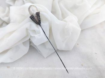 Voici une ancienne épingle à chapeaux de 13 cm de long décorée par une grande perle nacrée ovale et biscornue sertie par un habillage en métal argenté composé en trois parties ciselées pour la décorer comme un bijoux. Top vintage.