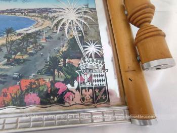 Datant des années 60, voici un plateau en bois clair serti par endroits de parties métalliques avec une vue de Nice, sa  Promenade des Anglais et l’Hôtel Négresco et recouvert d'une vitre aux décors miroir avec l'écusson de la Cote d’Azur.