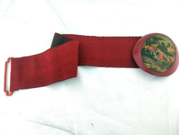 Sur la base d'un élastique en velours rouge de 56 cm de long à la base et 8.5 cm de large, voici une ceinture très originale et vraiment vintage des années 80/90 se ferme par une boucle en plastique épais représentant une scène de vie galante du XVIII°.