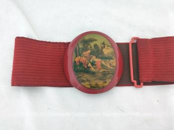 Sur la base d'un élastique en velours rouge de 56 cm de long à la base et 8.5 cm de large, voici une ceinture très originale et vraiment vintage des années 80/90 se ferme par une boucle en plastique épais représentant une scène de vie galante du XVIII°.