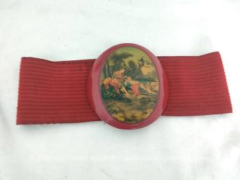 Sur la base d'un élastique en velours rouge de 56 cm de long à la base et 8.5 cm de large, voici une ceinture très originale et vraiment vintage des années 80/90 se ferme par une boucle en plastique épais représentant une scène de vie galante du XVIII°.