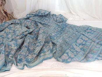 Voici un superbe tissus de 575 x 110 cm en soie bleue décoré d'arabesques et volutes encore avec son étiquette indiquant l'Artisana Made in India prévu pour réaliser un Sari.