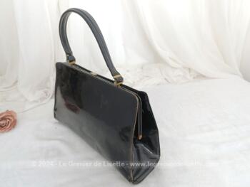 Voici un sac vintage en cuir vernis noir avec une poche intérieure simple et une fermée par une fermeture éclair. Il se ferme par un fermoir à clapet. Sa anse lui permet de le porter à la main, au bras et même à l'épaule. Top vintage !